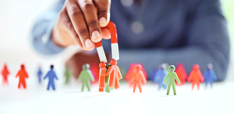 Manos que juntan con un imán figuras de personas Manos que juntan con un imán figuras de personas